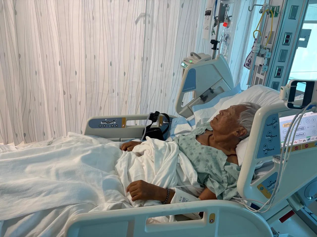 Dr. Ji resting in the ICU, monitors and IV at the bedside